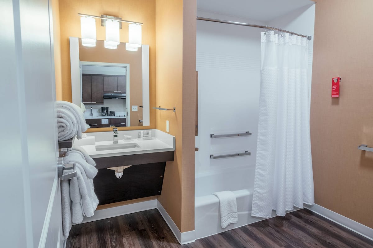 A modern bathroom with a sink, mirror, and shower curtain.
