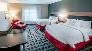 A hotel room with two beds, a red armchair, a small table, and a window with curtains. - TownePlace Suites Toledo Oregon (Oregon)