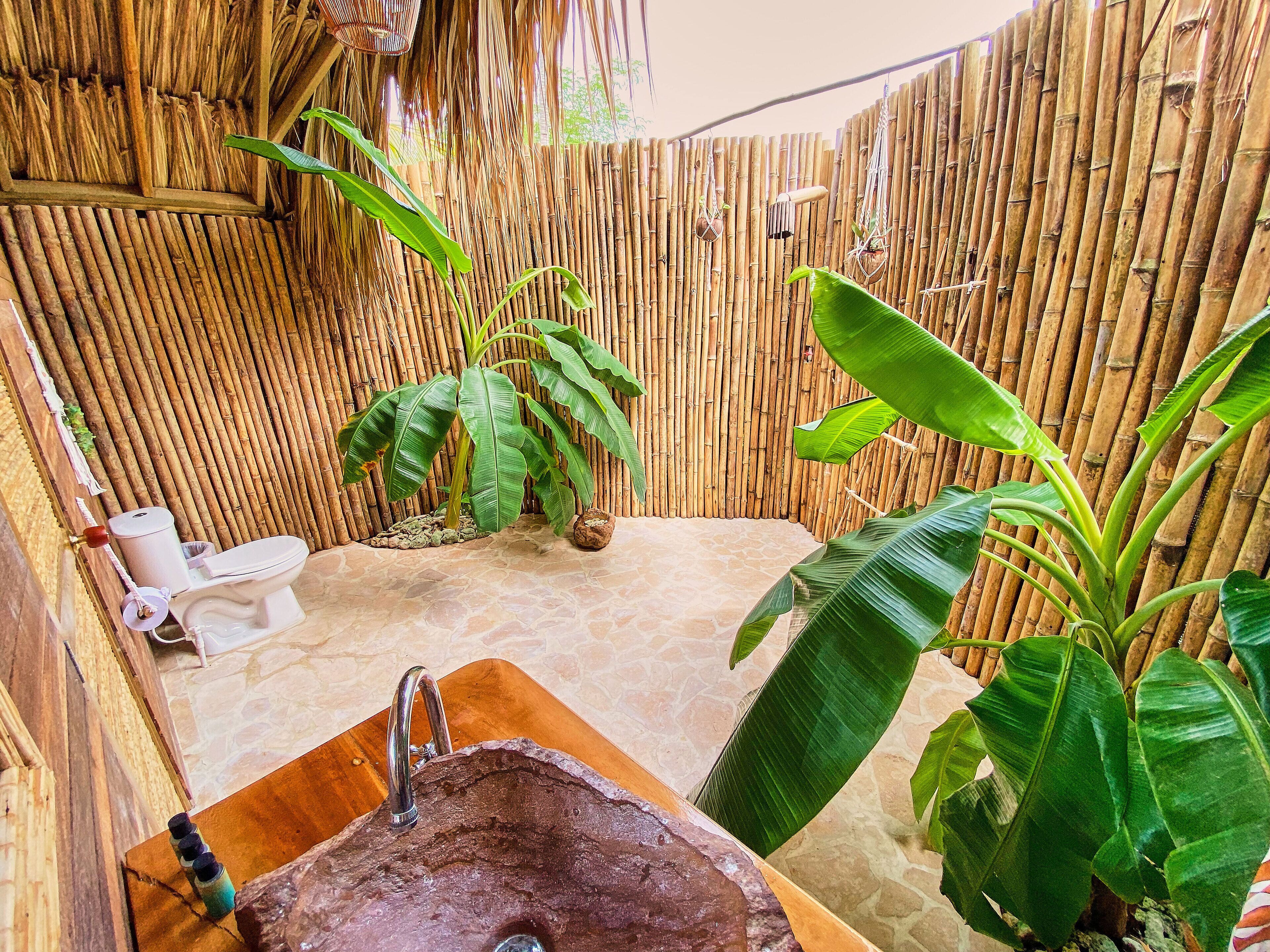 A bathroom with a stone sink, a toilet, and bamboo walls.