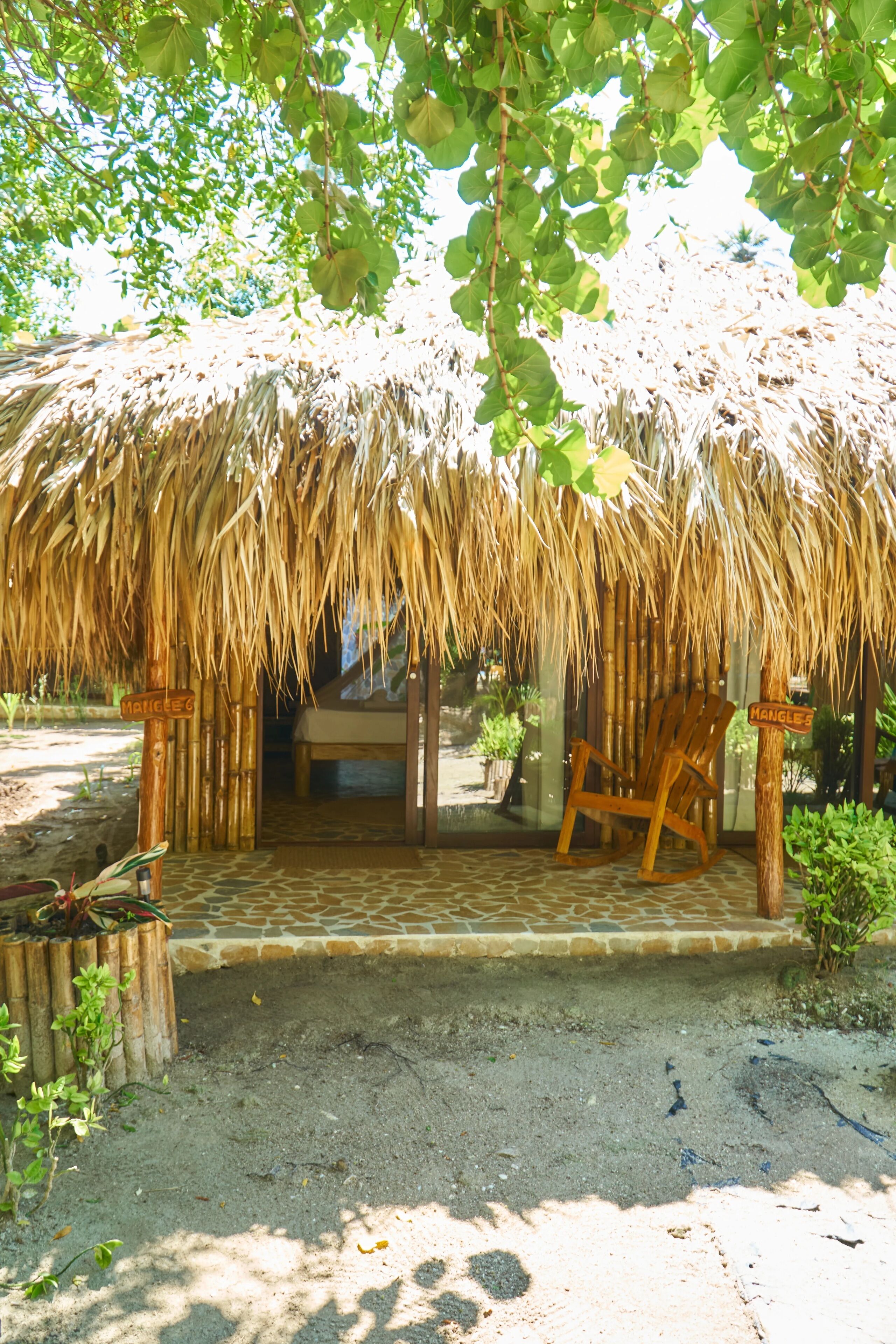 Una estructura con techo de paja, un banco de madera y un letrero que dice "HANGLE'S".