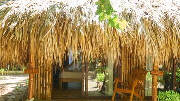 Una estructura con techo de paja, un banco de madera y un letrero que dice "HANGLE'S".