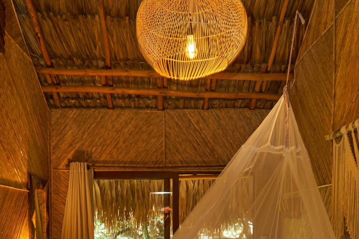 A room with a bed, a hanging light fixture, and a view of the outdoors.