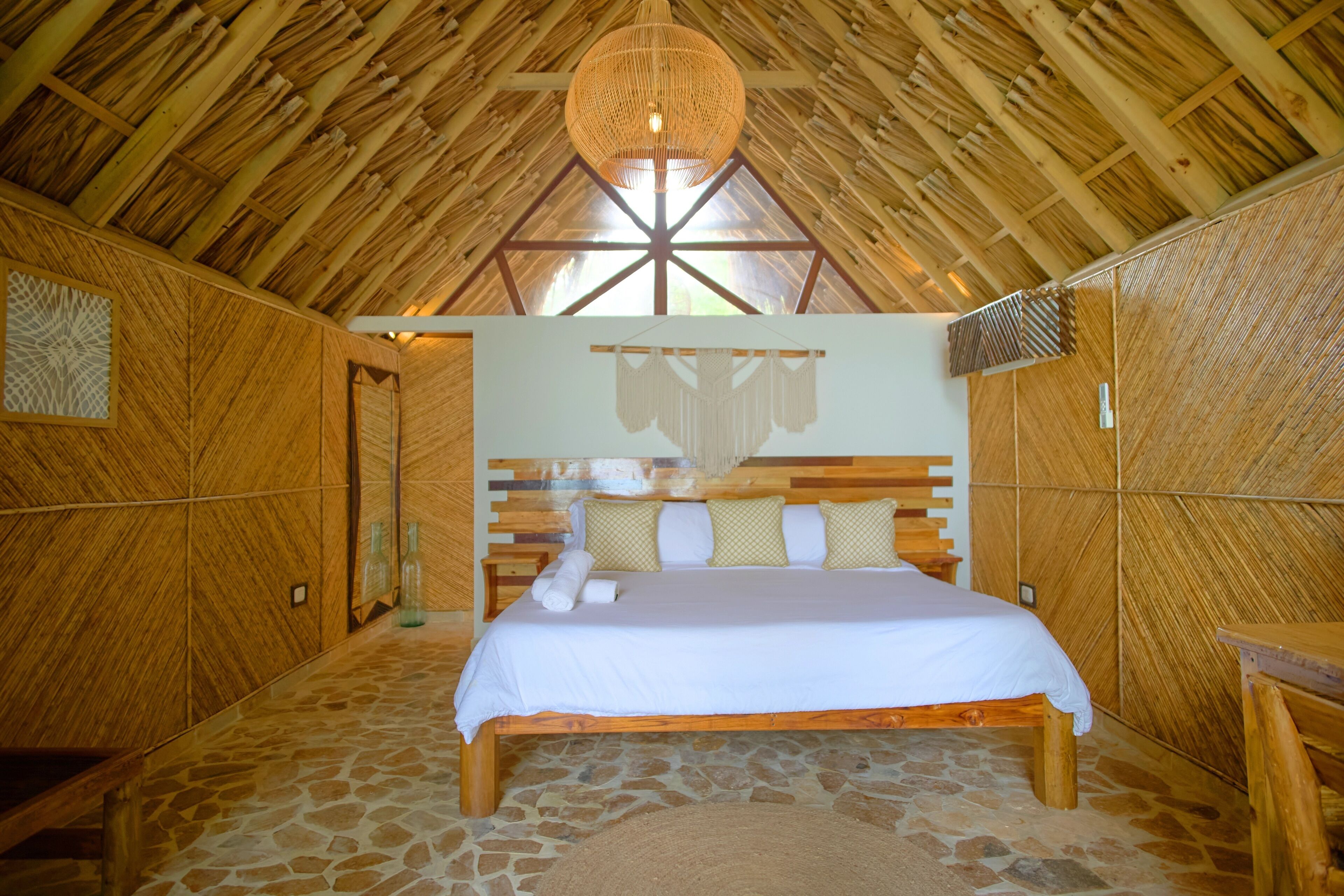 Une pièce en bois avec un lit, un sol en pierre et un plafond haut avec des poutres en bois.