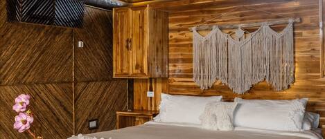 Une chambre à coucher rustique en bois, avec un grand lit, une décoration murale en macramé et un luminaire tressé.