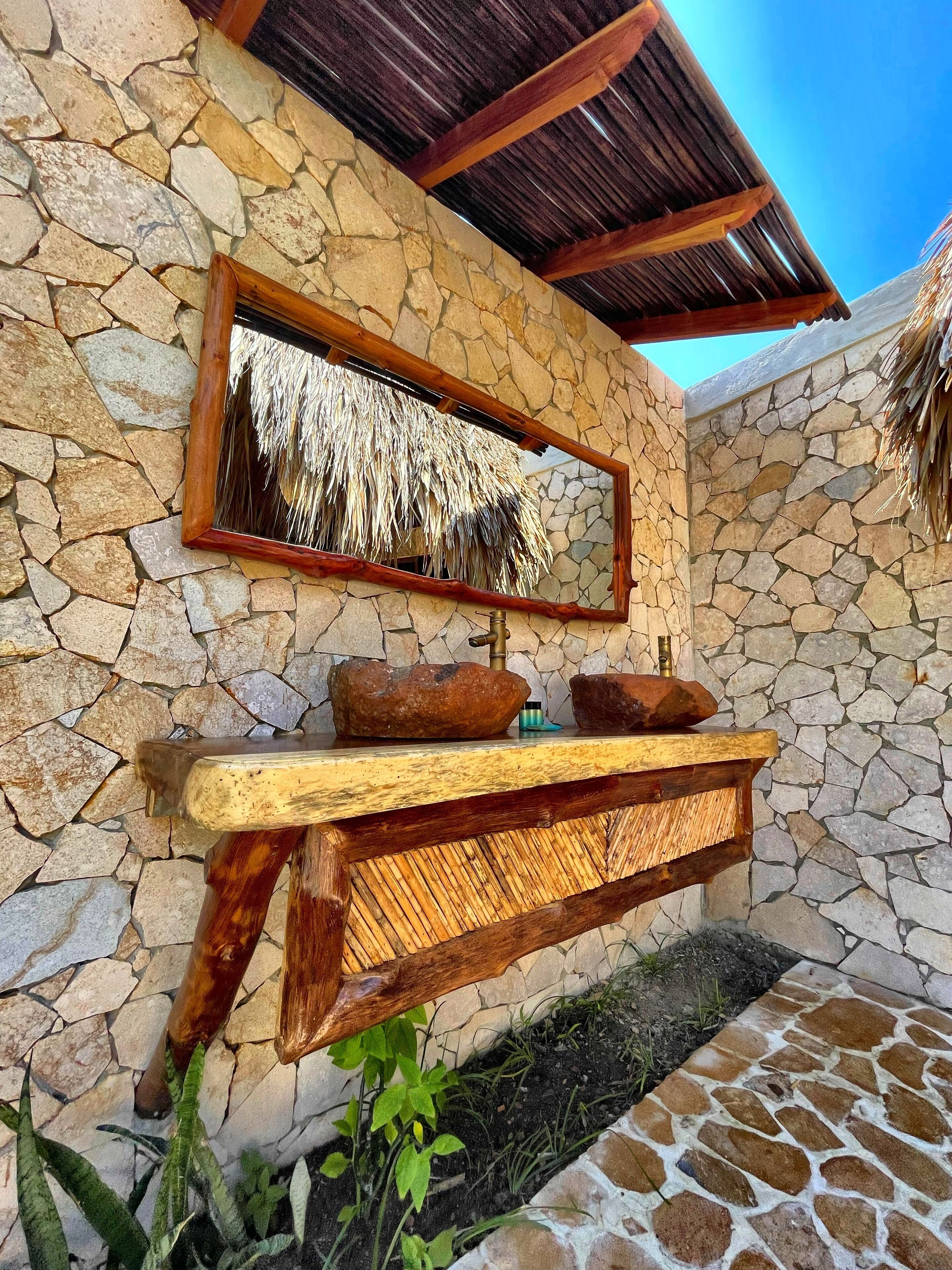 Un muro in pietra con una scaffalka in legno rustico che contiene un masso e un piccolo contenitore.