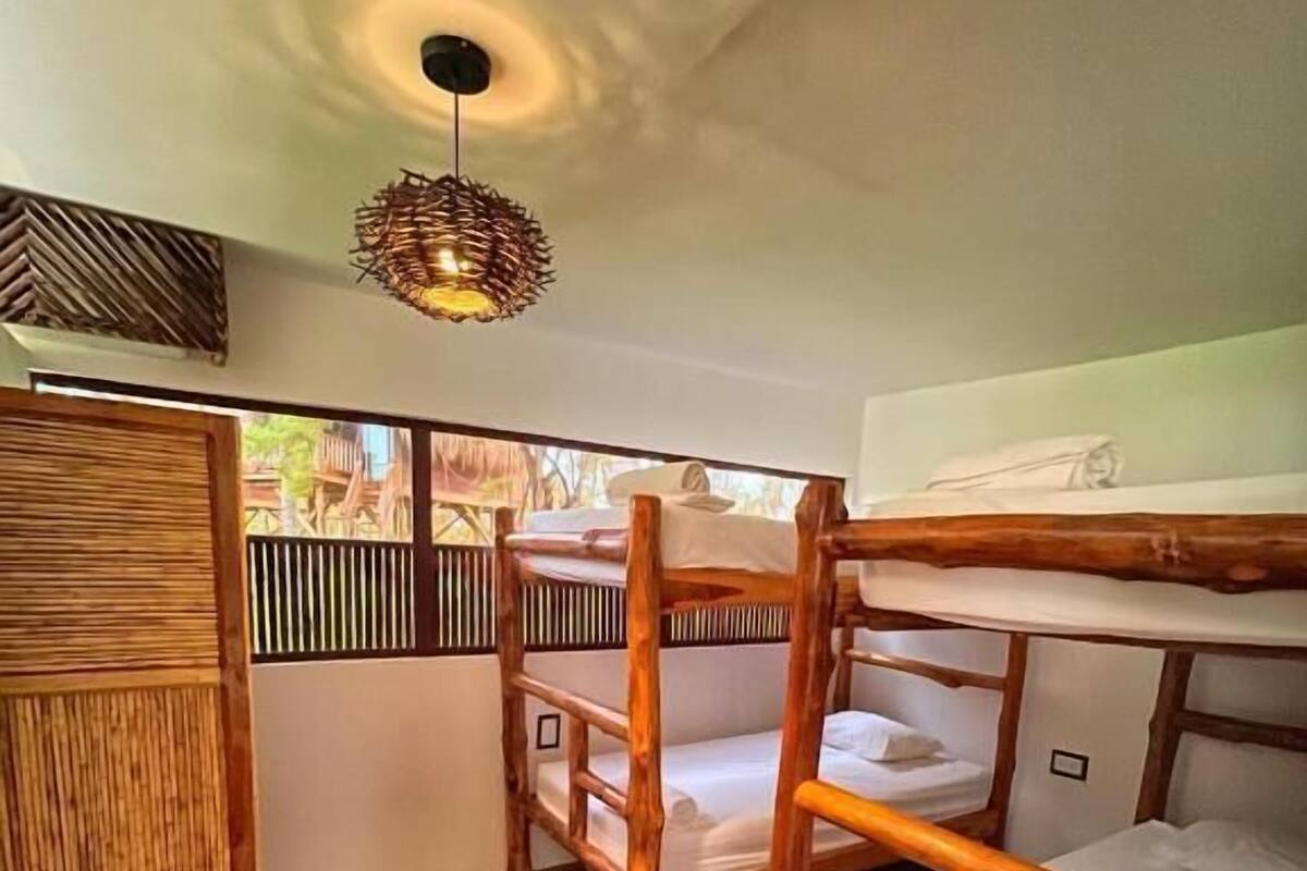 A bunk bed room with wooden flooring and a hanging light fixture.