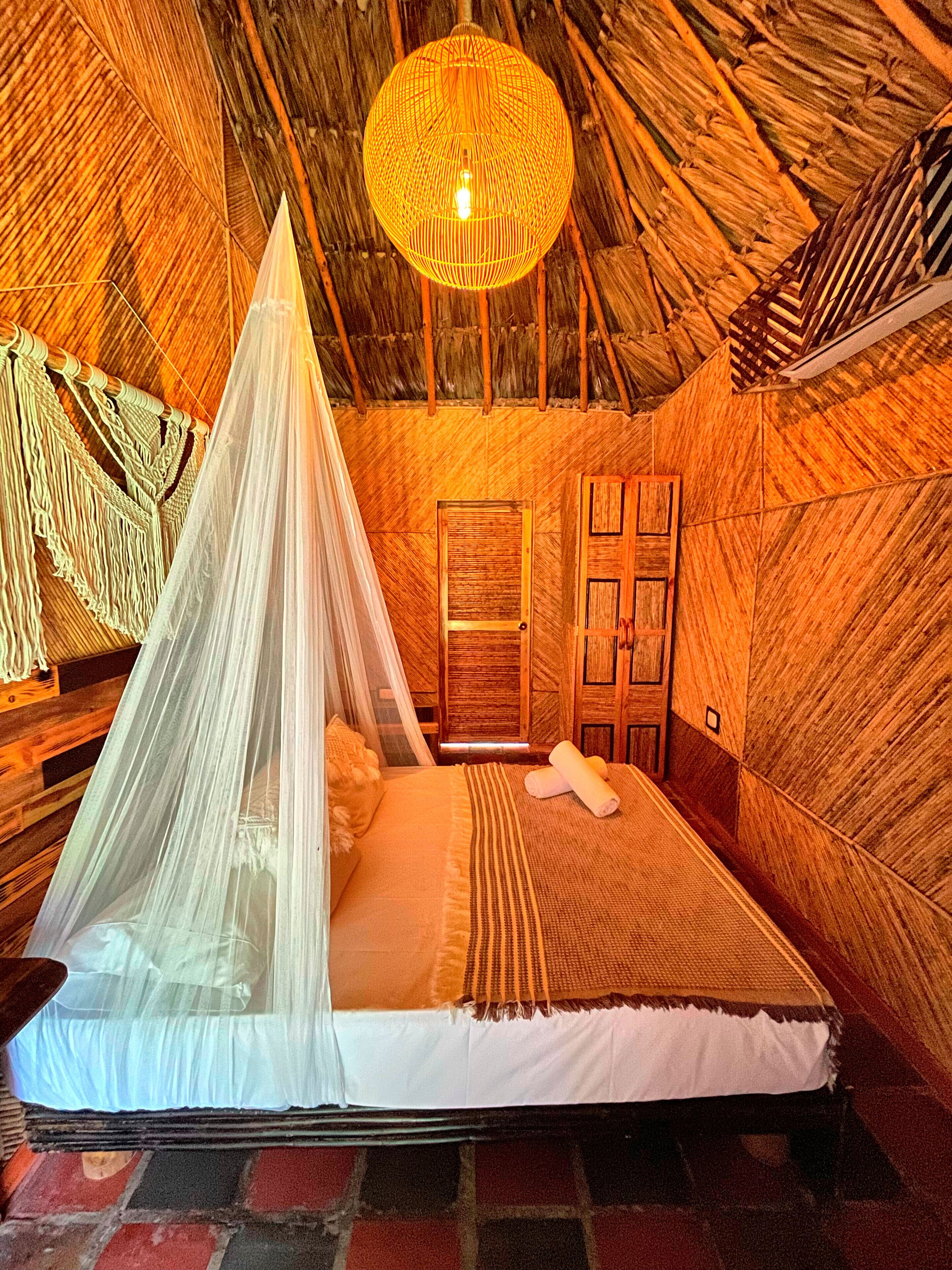 A room with a bed, a hanging light fixture, and a wooden door.