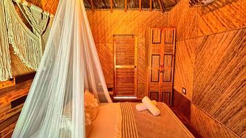 A room with a bed, a hanging light fixture, and a wooden door.