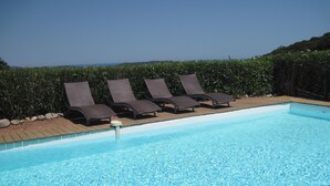 A clear blue pool with four lounge chairs aligned along the edge. - 7 BEDROOM HOUSE WITH AMAZING SEA VIEW AND SWIMMING POOL (Porto-Vecchio)