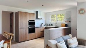 A modern kitchen with wooden cabinets, a built-in oven, and a window above the sink. - 7 BEDROOM HOUSE WITH AMAZING SEA VIEW AND SWIMMING POOL (Porto-Vecchio)