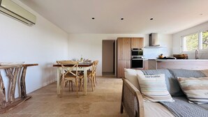 A modern, open-plan living space with a dining area, kitchenette, and a large bed with multiple pillows. - 7 BEDROOM HOUSE WITH AMAZING SEA VIEW AND SWIMMING POOL (Porto-Vecchio)