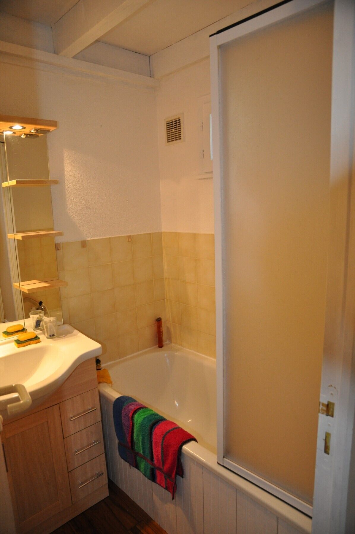 Une salle de bain avec une baignoire, un lavabo avec un miroir et une serviette accrochée au mur.