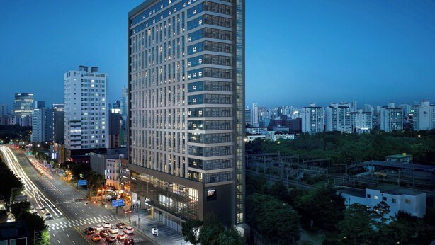 Un hotel moderno de altura con múltiples pisos y grandes ventanales.