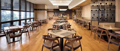 Un restaurante espacioso con numerosas mesas y sillas, amplias ventanas y una decoración de diseño moderno.