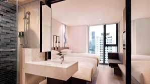 Una habitación de hotel moderna con un ventanal grande, ducha, cama y mesita de noche con espejo.