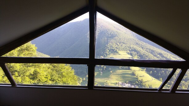 A room with a large window offering a view of a mountainous landscape. - Gites des Pics: the Black Pic - panoramic view (Riverenert)