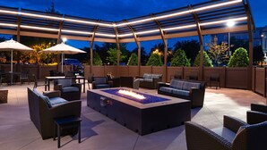 Une terrasse extérieure dotée d’un foyer, de sièges et de parasols.