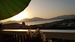 Ein Balkon mit Blick auf das Meer und die Berge bei Sonnenuntergang.
