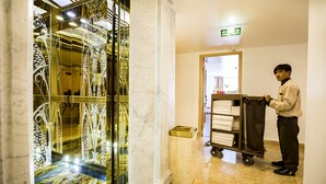 A hotel lobby with a marble floor, a decorative glass partition, and a cart with towels. - BEAUTIFUL SAPA HOTEL (Sa Pa)