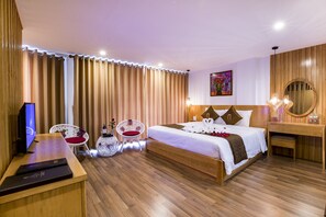 A hotel room with a wooden bed, a desk with a computer, a chair, and a small table with a vase. - BEAUTIFUL SAPA HOTEL (Sa Pa)