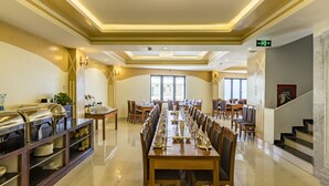 A spacious dining area with long tables set for multiple guests, a buffet on the left, and a staircase on the right. - BEAUTIFUL SAPA HOTEL (Sa Pa)