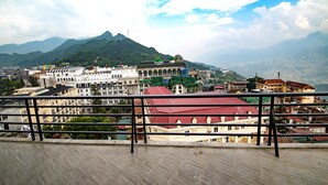 A cityscape with a mountain in the background, buildings with various architectural styles, and a clear sky. - BEAUTIFUL SAPA HOTEL (Sa Pa)