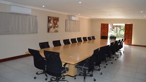 A conference room with a long table, black chairs, and two air conditioning units on the wall. - Airport Garden Boutique Hotel (Boksburg)