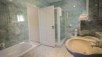 A bathroom with a bathtub, a shower enclosure, and a sink.