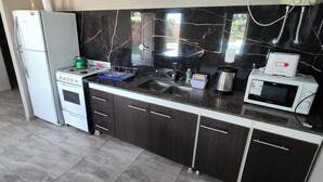Een praktische keuken met een gasfornuis, een magnetron en een spoelbak.