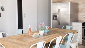 Una mesa de madera con sillas, un cuenco de flores y una botella de agua.