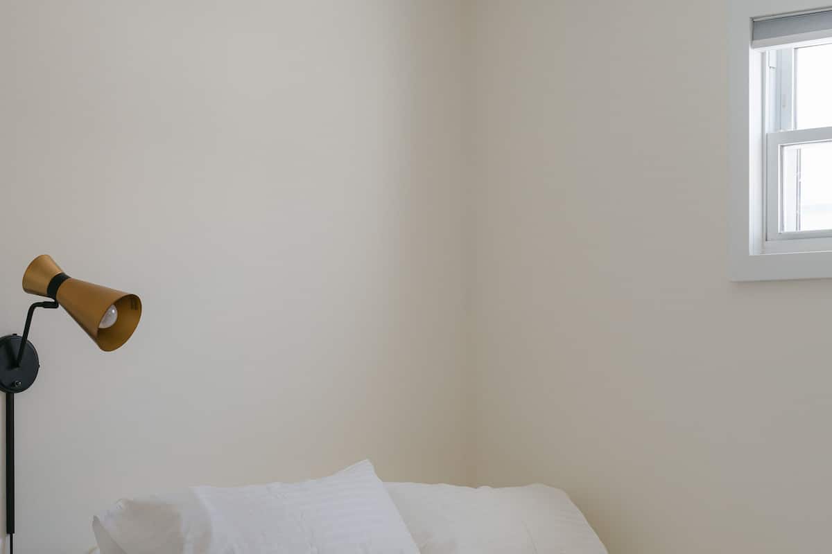 Habitación de hotel con dos camas, una lámpara y un ventanal.