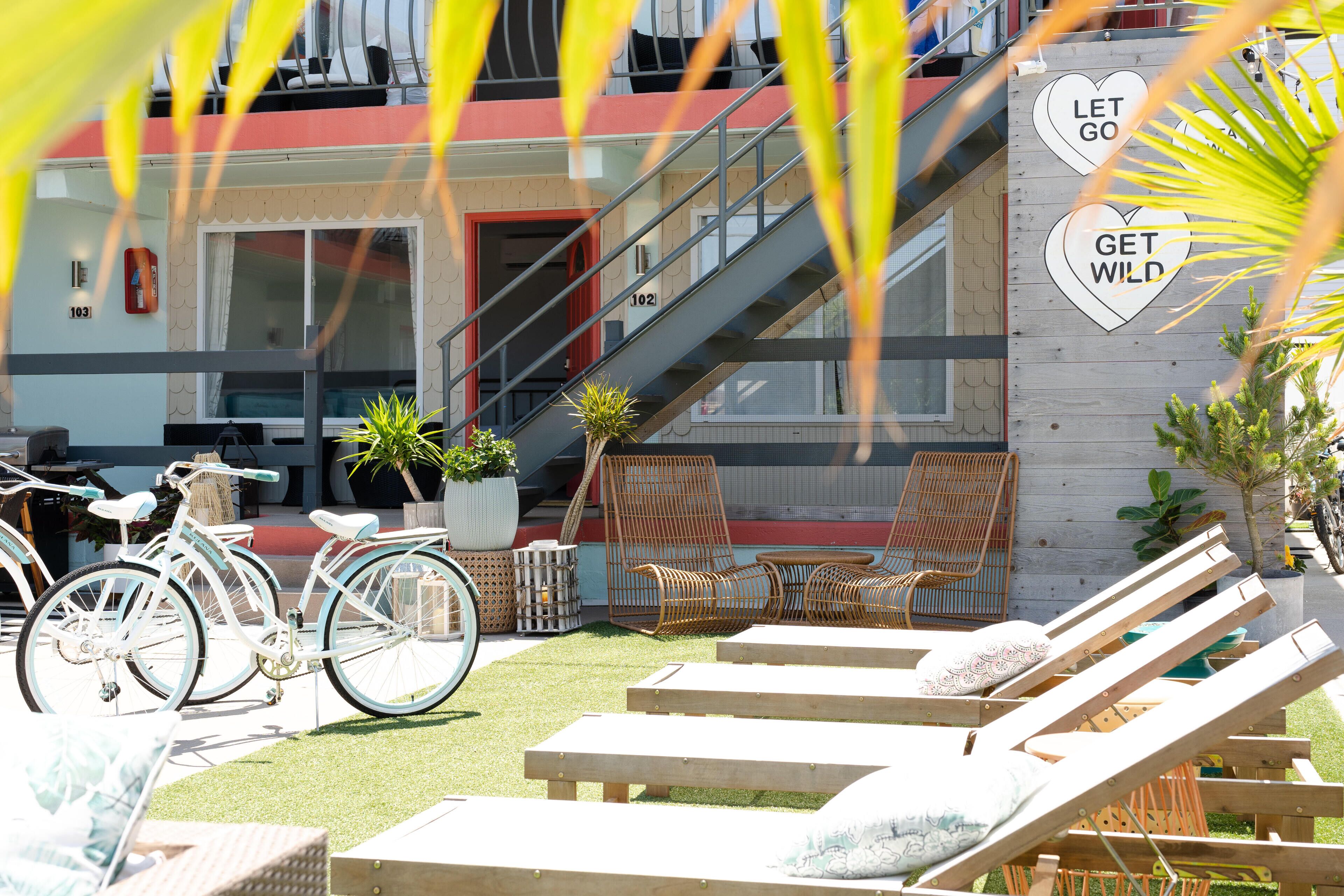 A hotel exterior with a staircase, lounge chairs, and a bicycle.
