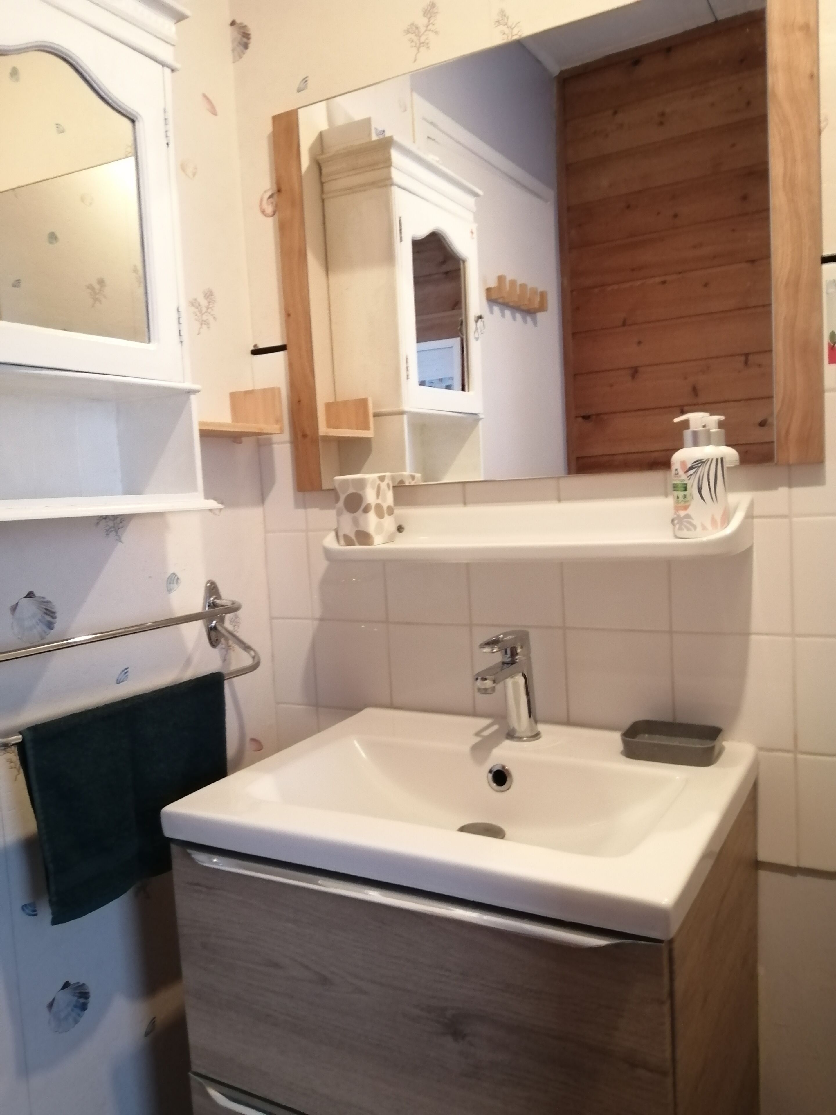 A bathroom with a white sink, a mirror, and a wooden vanity.