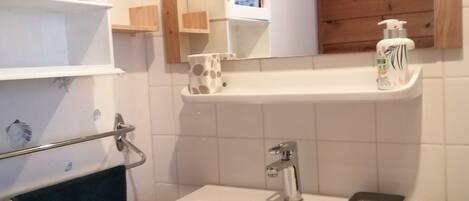 A bathroom with a white sink, a mirror, and a wooden vanity.