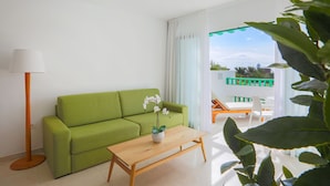 A green sofa, a wooden coffee table, and a potted orchid. - Nazaret Apartments (Teguise)