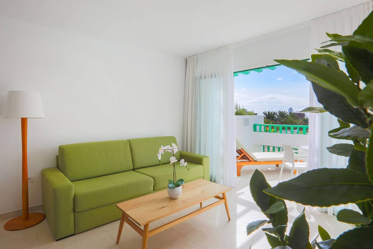 Ein grünes Sofa, ein Holztisch und eine Orchidee im Blumentopf.