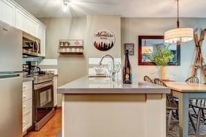 A modern kitchen with a central island, stainless steel appliances, and a dining area with a wooden table and chairs.