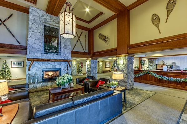 A lobby with stone walls, a fireplace, leather seating, and a Christmas tree.