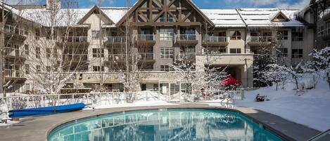 Un hôtel doté d’une piscine, entouré d’arbres couverts de neige, et offrant une vue sur un ciel bleu et dégagé.
