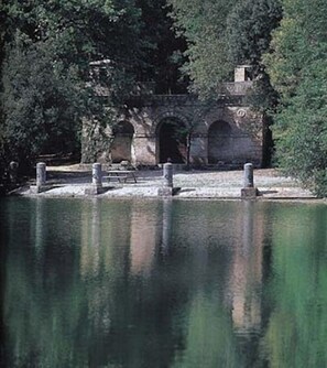 A stone bridge with arches over a body of water, surrounded by trees. - Charming Tuscany Villa with magical Garden, shared pool,  Chianti Area  (Castelnuovo Berardenga)