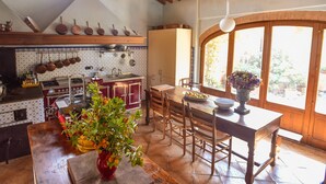 A kitchen with wooden cabinets, a dining table, and a large window. - Charming Tuscany Villa with magical Garden, shared pool,  Chianti Area  (Castelnuovo Berardenga)