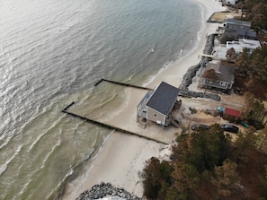Vue aérienne d’une propriété située en bord de mer, avec une maison, une jetée et une côte rocheuse.