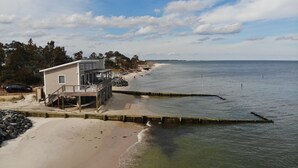 A beach house with a deck and a view of the ocean. - Modern Beachfront Cottage with Endless Bay Views (Port Haywood)
