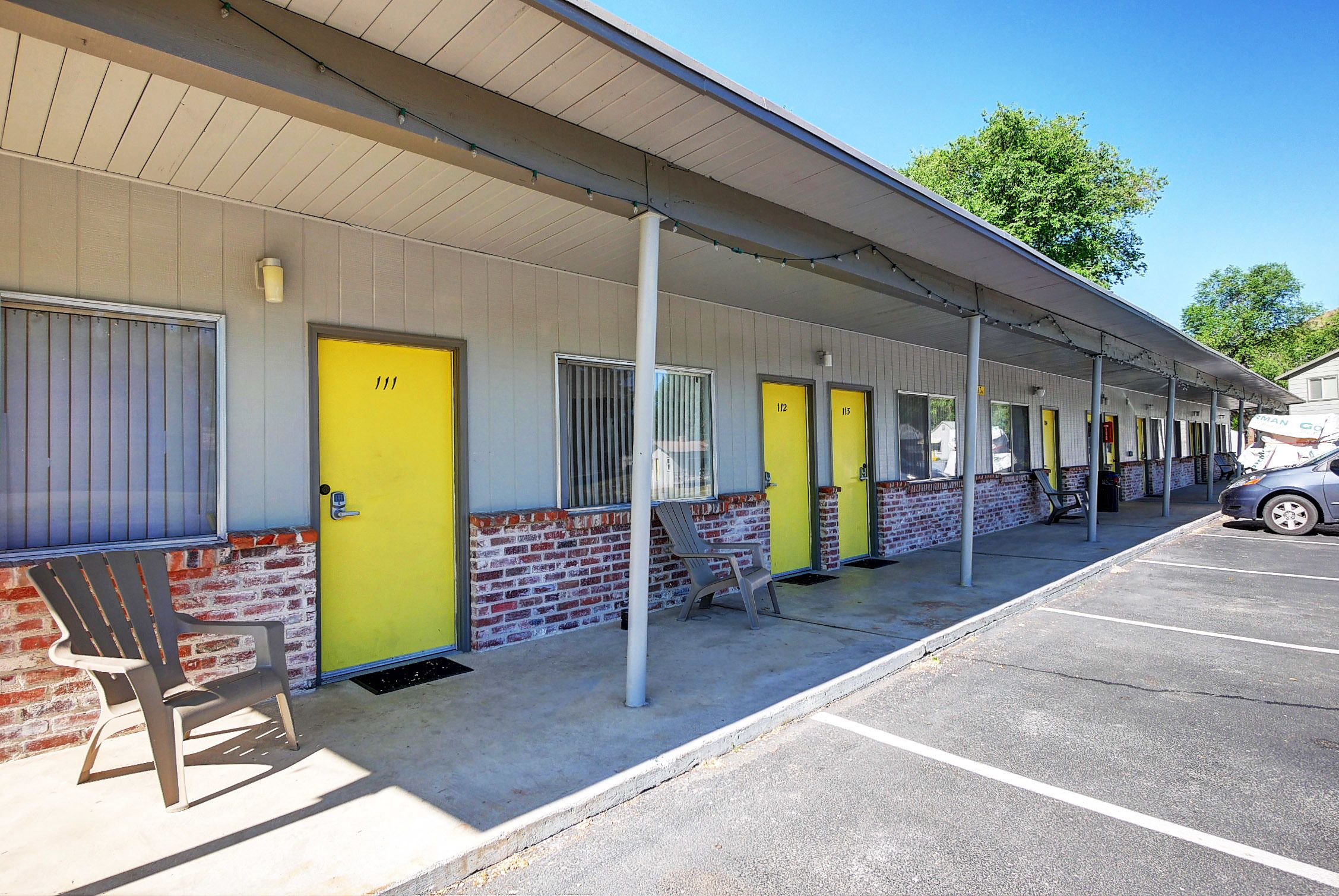 A motel with a row of rooms, each with a yellow door and a window.