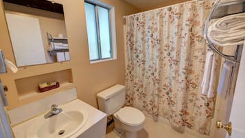 Un baño con lavamanos, inodoro y cortina de ducha.