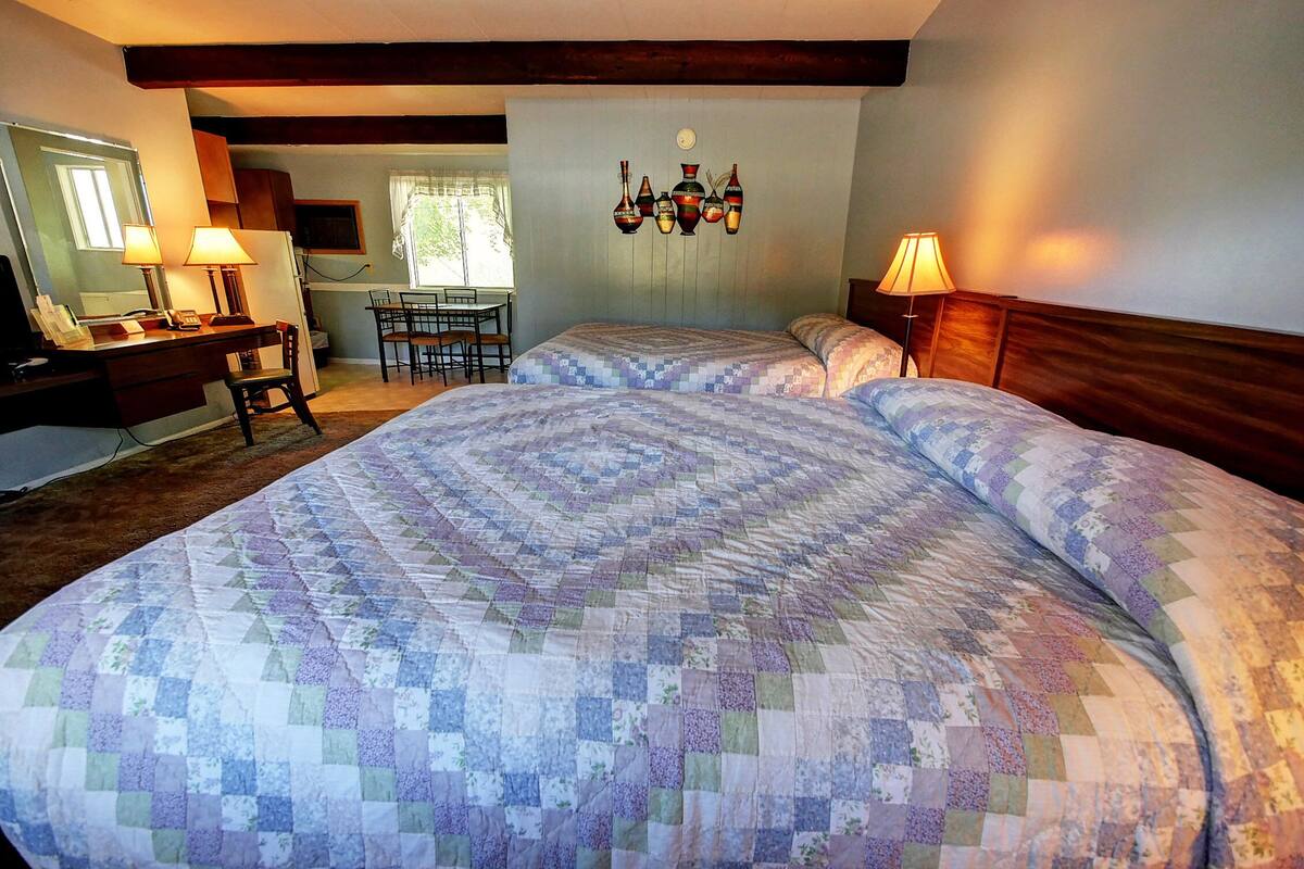 A bedroom with a large bed, a desk with a chair, and a dining area.