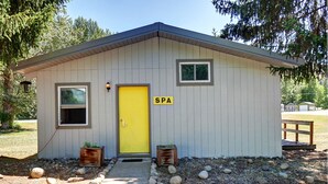 A small building with a yellow door labeled "SPA," two windows, and a small porch area with potted plants. - Idle A While (Twisp)