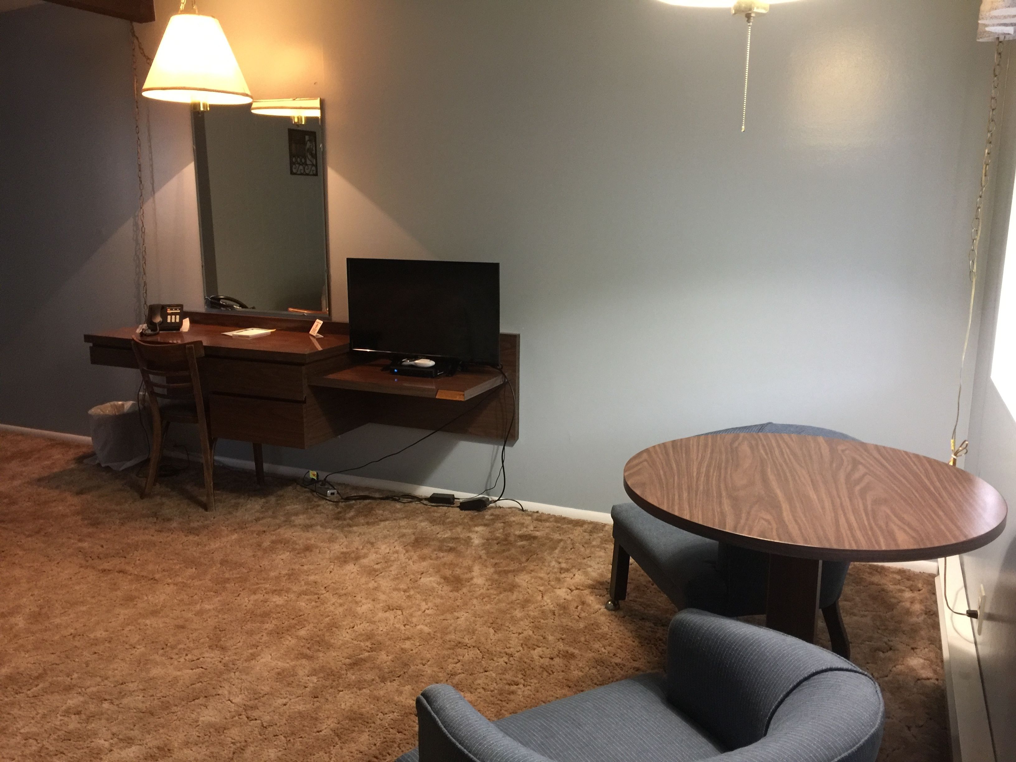 Una habitación con escritorio, silla y una mesa redonda.