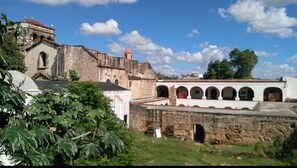 A historic stone building with arches and a red-roofed tower. - Hostal Arboleda (Santo Domingo)