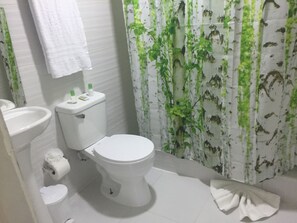 A bathroom with a toilet, sink, and shower curtain. - Hostal Arboleda (Santo Domingo)